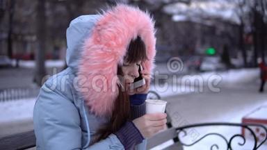 冬天，一个穿着灰色<strong>保暖</strong>夹克的年轻女人在街上用电话。